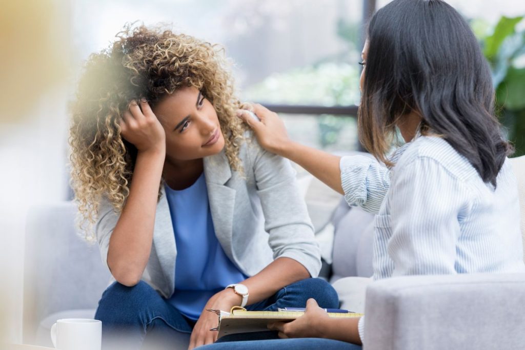 Two professionals in a supportive conversation, with one person offering reassurance.